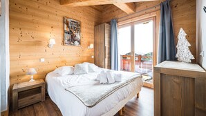 Habitación con paneles de madera, una cama, una mesita de noche y vistas al exterior.