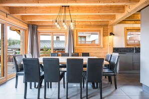 A modern dining area with a wooden ceiling, large windows, and a view of a building outside.