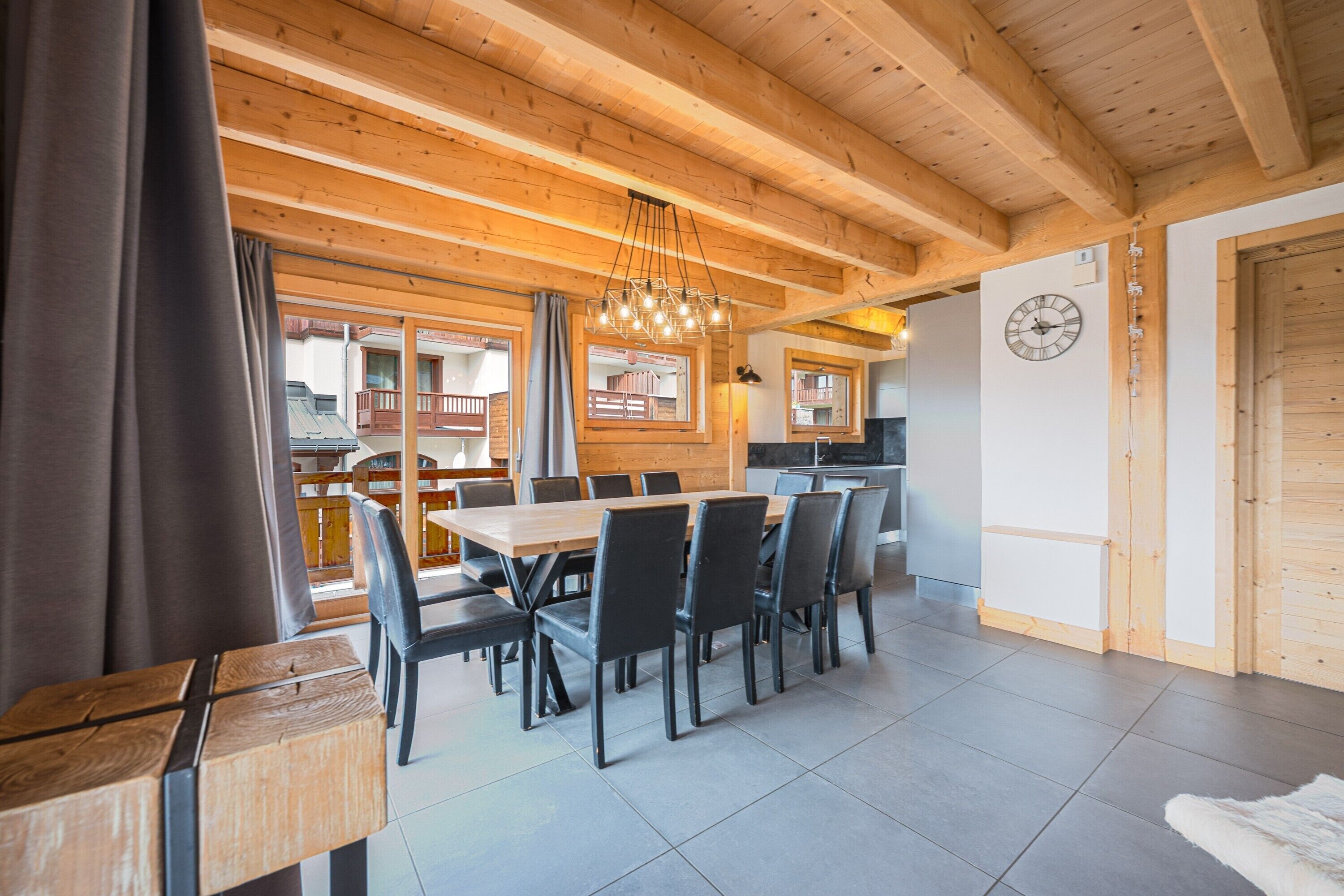 A wooden interior with a dining table, chairs, and a kitchen area.