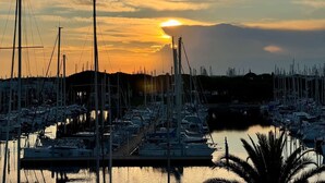 A marina with multiple boats docked, a clear sky, and a sunset in the background. - Spacious 3 room air-conditioned apartment terrace garage (LE GRAU DU ROI)