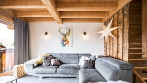 A modern living room with a grey sectional sofa, a star-shaped wall decoration, and a wooden ceiling. - Apartment 'Chalet B - o Saisies' with Mountain View, Balcony and Wi-Fi (Les saisies)