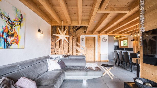 A modern living room with a gray sectional sofa, a wooden ceiling, and a staircase leading to an upper level. - Apartment 'Chalet B - o Saisies' with Mountain View, Balcony and Wi-Fi (Les saisies)