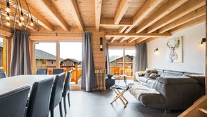 A wooden interior with a dining area, sofa, and artwork on the wall. - Apartment 'Chalet B - o Saisies' with Mountain View, Balcony and Wi-Fi (Les saisies)