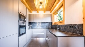 A modern kitchen with built-in appliances, a window, and a wooden ceiling. - Apartment 'Chalet B - o Saisies' with Mountain View, Balcony and Wi-Fi (Les saisies)