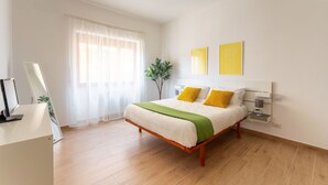 A bedroom with a bed, bedside table, lamp, and two wall-mounted artworks.