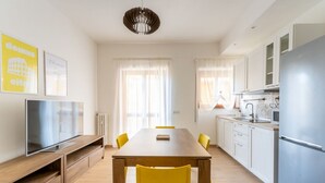 A modern kitchen with white cabinets, a built-in oven, and a stainless steel refrigerator.