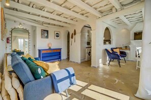 A spacious living area with a sofa, chairs, a blue console table, and a kitchen in the background. - Apartment 'Golf Course View' with Mountain View, Wi-Fi and Air Conditioning (Las Lagunas de Mijas)