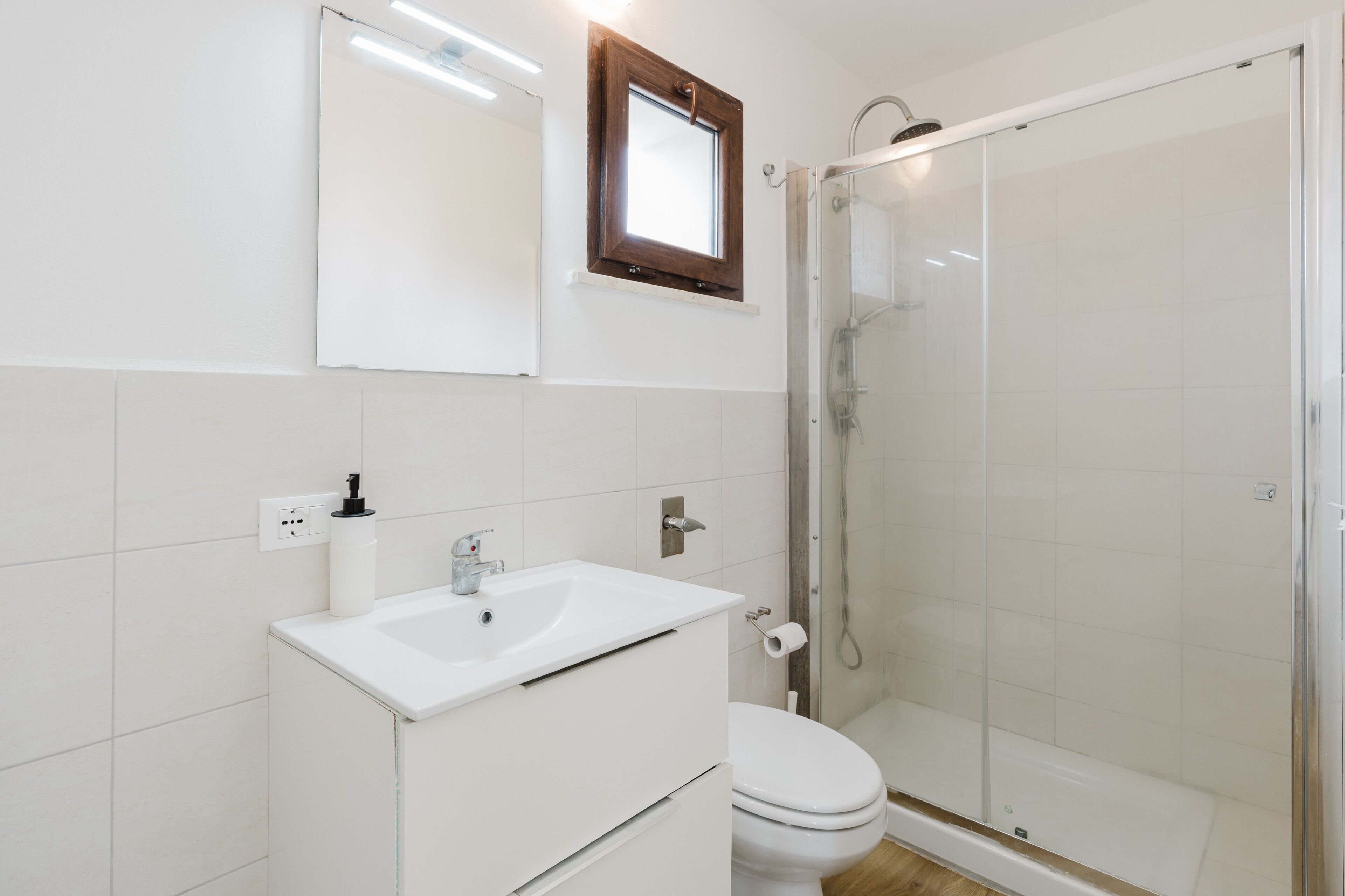 Un bagno con un lavandino bianco, un WC e una cabina doccia in vetro.