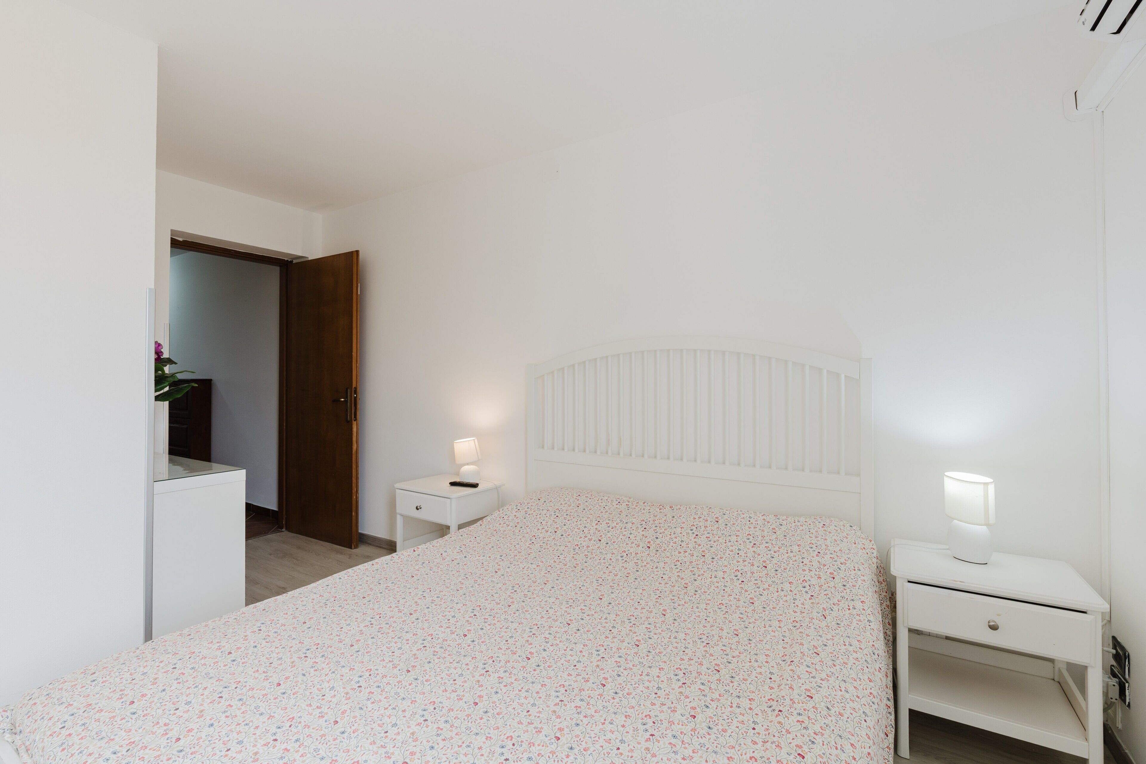 Una camera da letto con un letto, un comodino, una cassettiera e una porta.