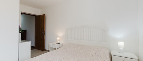 A bedroom with a bed, a nightstand, a dresser, and a door.