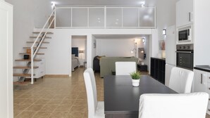 A modern kitchen with a dining area, a staircase, and a living space.