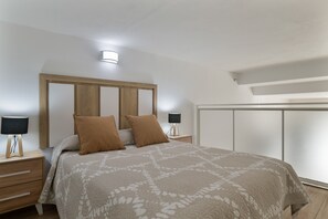Un dormitorio con una cama, mesitas de noche, un cabecero de madera y un armario.