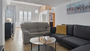 A modern living room with a sofa, a coffee table, and a painting of a cityscape.