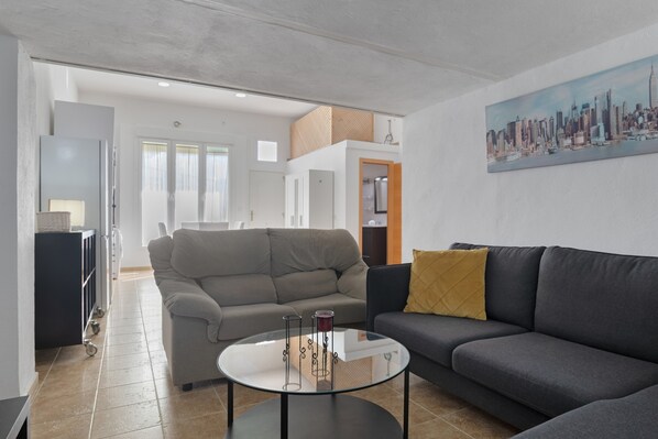 A modern living room with a sofa, a coffee table, and a painting of a cityscape.