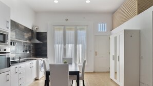 A modern kitchen with a dining area, a washing machine, and a door leading to another room.