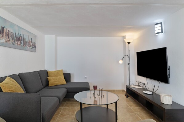 Una sala de estar moderna con un sofá, una mesa de centro, un televisor de pantalla plana y una lámpara de pie.