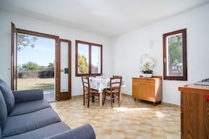 Una habitación con una mesa de comedor, sillas, un sofá, un armario y una ventana.