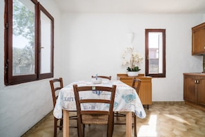 Un comedor con una mesa, sillas, una ventana y una zona de cocina.
