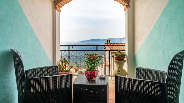 Un balcon avec des fauteuils en osier, une table et des plantes en pot.