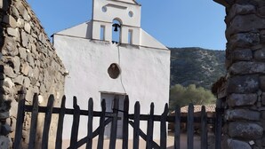 Une église blanche avec un clocher, une porte en bois et un mur de pierre.