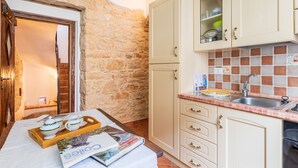 Una cocina con paredes de piedra, armarios de madera y salpicadero de azulejos.