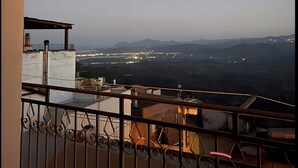 Un balcón con vistas a luces distantes de la ciudad y montañas.