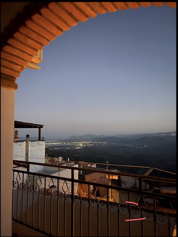 Un balcón con vistas a luces distantes de la ciudad y montañas.