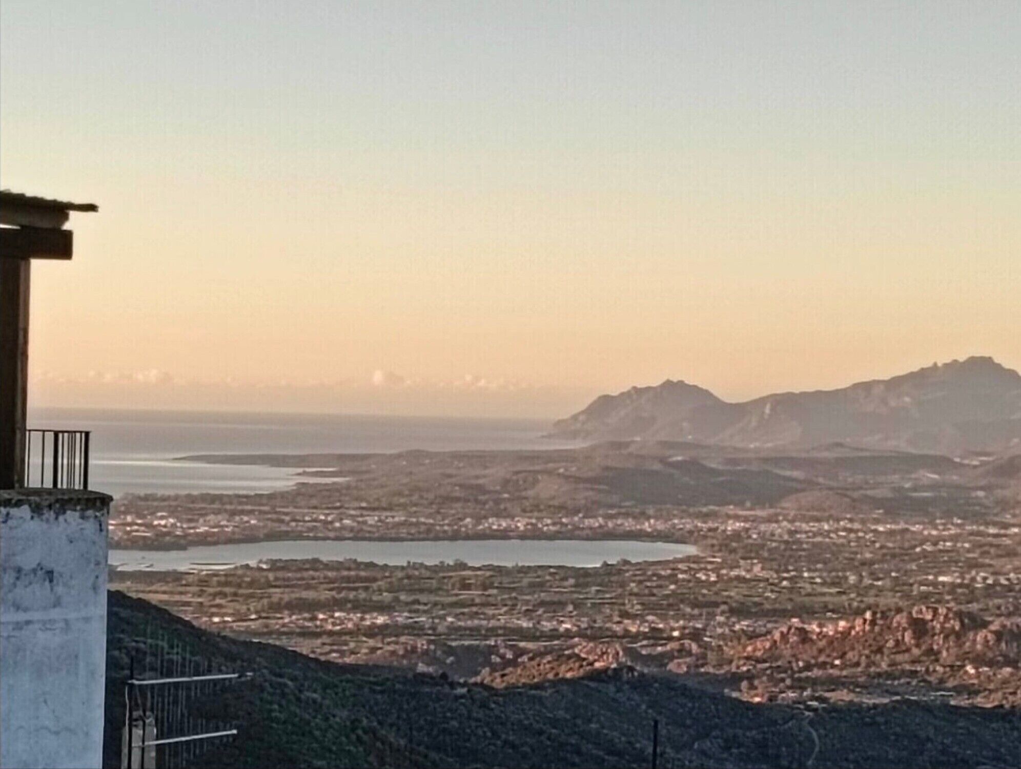 Une vue panoramique d’une ville côtière, avec une chaîne de montagnes imposante en arrière-plan.