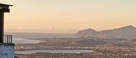 Une vue panoramique d’une ville côtière, avec une chaîne de montagnes imposante en arrière-plan.