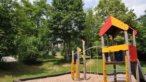 A playground with climbing structures and a slide, surrounded by trees and a grassy area. - Nawal's Belle Vue Dinant/Givet (Hastière)