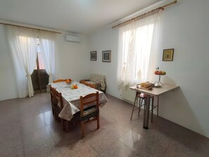 Zona pranzo con tavolo, sedie, un tavolino con lampada e un termosifone.