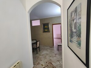 Un corridoio stretto con un arco che conduce a una stanza con un letto e una sedia.