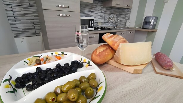 A kitchen with a plate of olives, bread, cheese, and a bottle of wine. - Apartment 'A Matrice' with Balcony, Wi-Fi and Air Conditioning (Barrafranca)