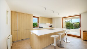 Une cuisine moderne avec des meubles en bois, un plan de travail blanc et une grande fenêtre.