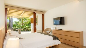 Une chambre avec un lit, une télévision, une commode en bois et une vue sur la verdure.