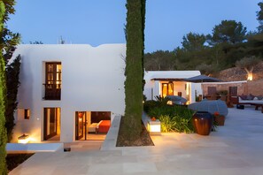 Una casa moderna con patio, area salotto esterna e ingresso ben illuminato.