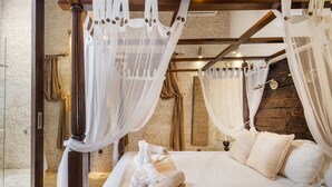 A bedroom with a canopy bed, a stone wall, and a wooden ceiling. - Beautiful luxury villa in Ibiza with Wi-Fi and air conditioning (Illes Balears)