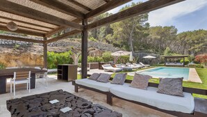 An outdoor patio with a pool, wooden furniture, and a stone table. - Beautiful luxury villa in Ibiza with Wi-Fi and air conditioning (Illes Balears)