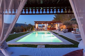A pool with a pergola and outdoor seating area.