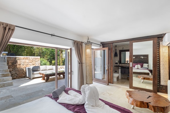 A spacious room with a bed, a wooden coffee table, and a large mirror reflecting the room.