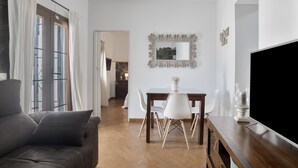 Un salon moderne avec un canapé, une table à manger, des chaises, un téléviseur et un miroir au mur.