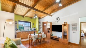 Un amplio salón con techo de madera, una mesa de comedor y un televisor.