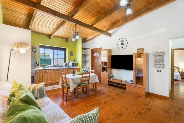 Un vaste espace de vie doté d’un plafond en bois, d’une table à manger et d’un téléviseur.