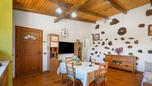 Comedor con mesa de madera, sillas, un reloj y una pared de piedra.
