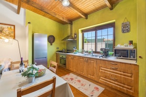 Une cuisine avec des meubles de rangement en bois, un réfrigérateur, un four à micro-ondes et une fenêtre donnant sur un beau paysage.