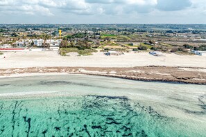 Vista aérea de una zona costera con aguas turquesas cristalinas, playas de arena y edificios dispersos.