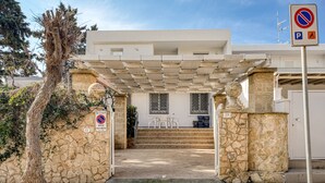 A building entrance with a stone wall, a tree, and a no parking sign. - Holiday Home 'Luce Sulla Spiaggia' with Private Garden and Air Conditioning (Torre San Giovanni)