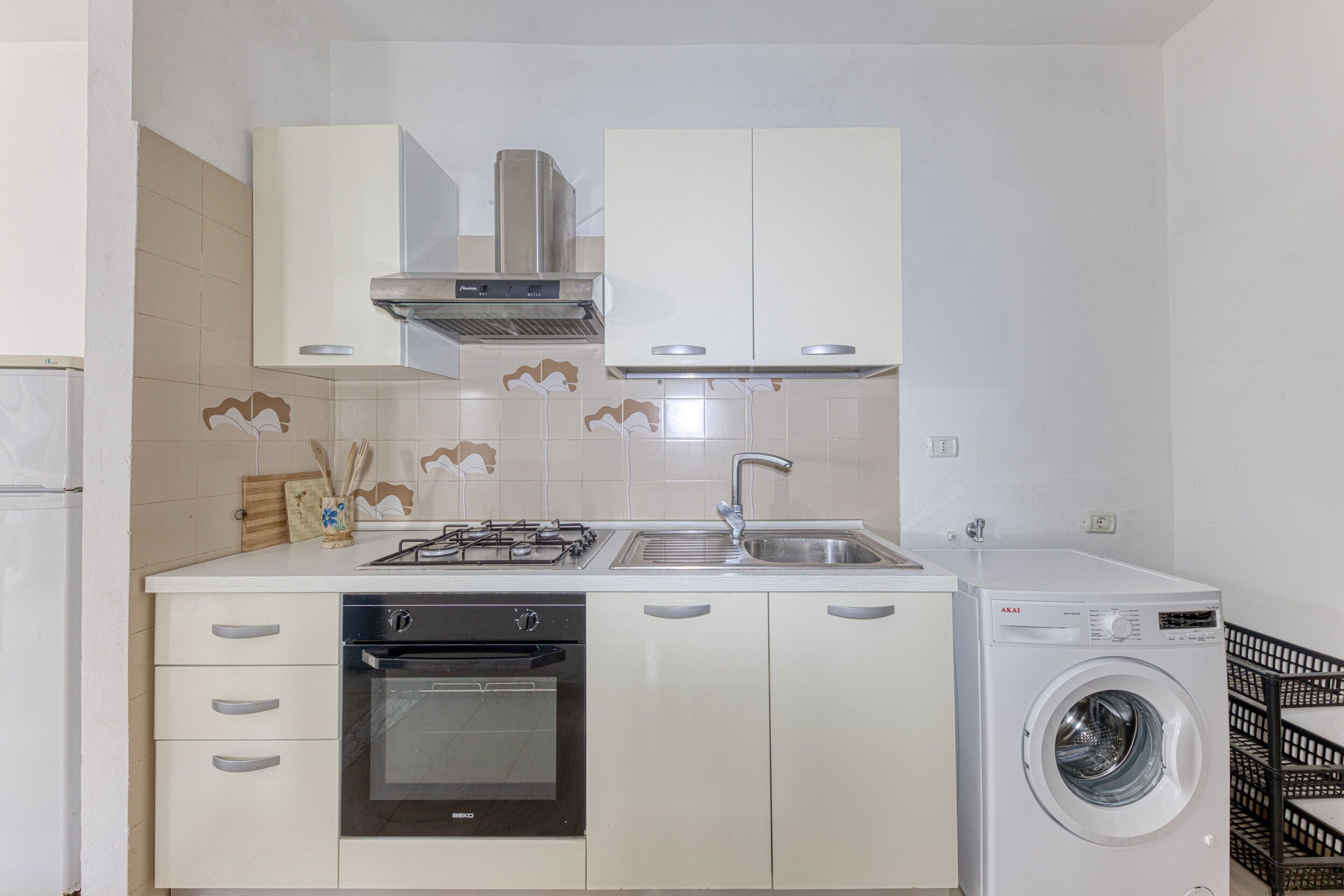 Une cuisine compacte équipée d’une cuisinière à gaz, d’un four, d’un évier et d’un lave-linge encastré.