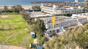 A coastal building with multiple floors, a parking area, and a view of the sea. - Holiday Home 'Luce Sulla Spiaggia' with Private Garden and Air Conditioning (Torre San Giovanni)
