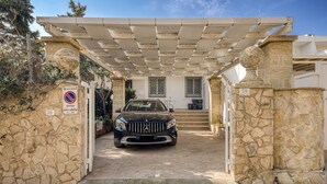 A stone-carved entrance with a car parked inside, a no parking sign, and a building with a tiled roof. - Holiday Home 'Luce Sulla Spiaggia' with Private Garden and Air Conditioning (Torre San Giovanni)